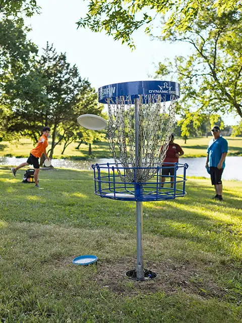 A group of people playing disc golf